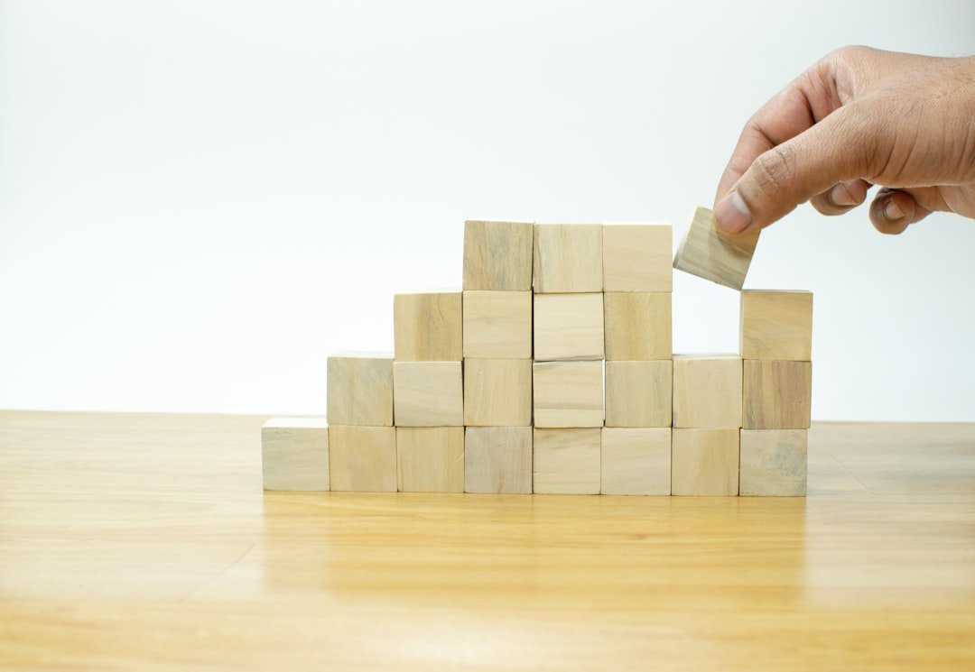 Home Hand arranging wood block stacking as step stair on wooden table, Business concept for growth success process.